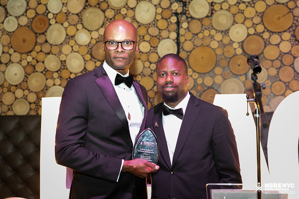 Two NSBE NYC honorees holding an award on the gala stage